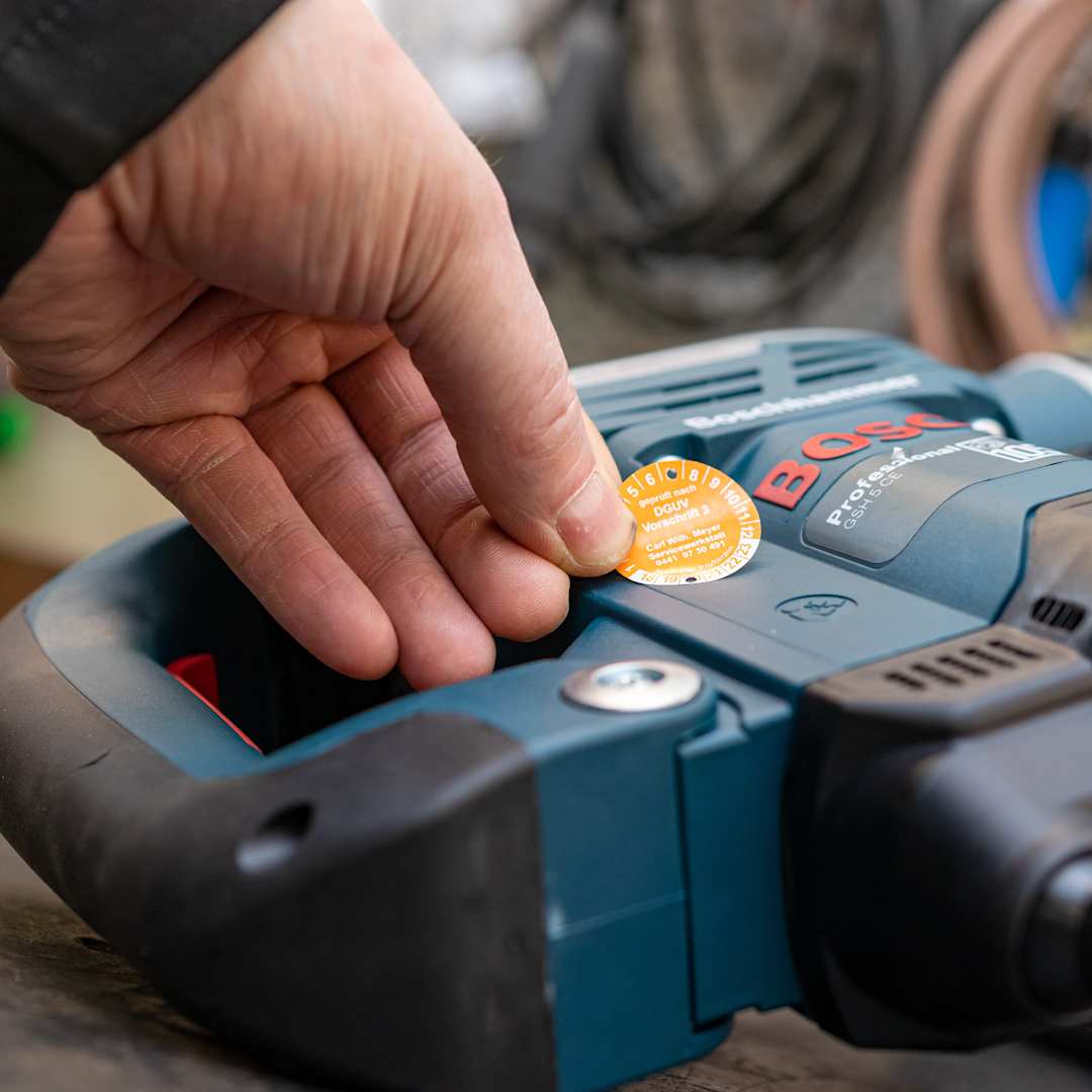 Aufkleber Betriebsmittelprüfung wird auf Gerät geklebt